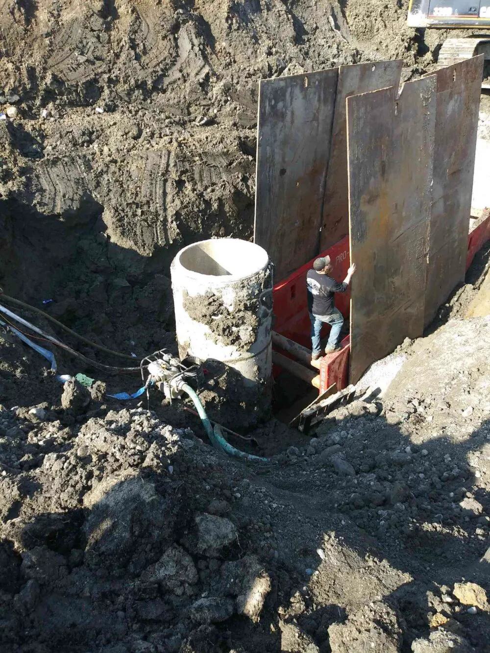 Worker setting a structure in a shored trench