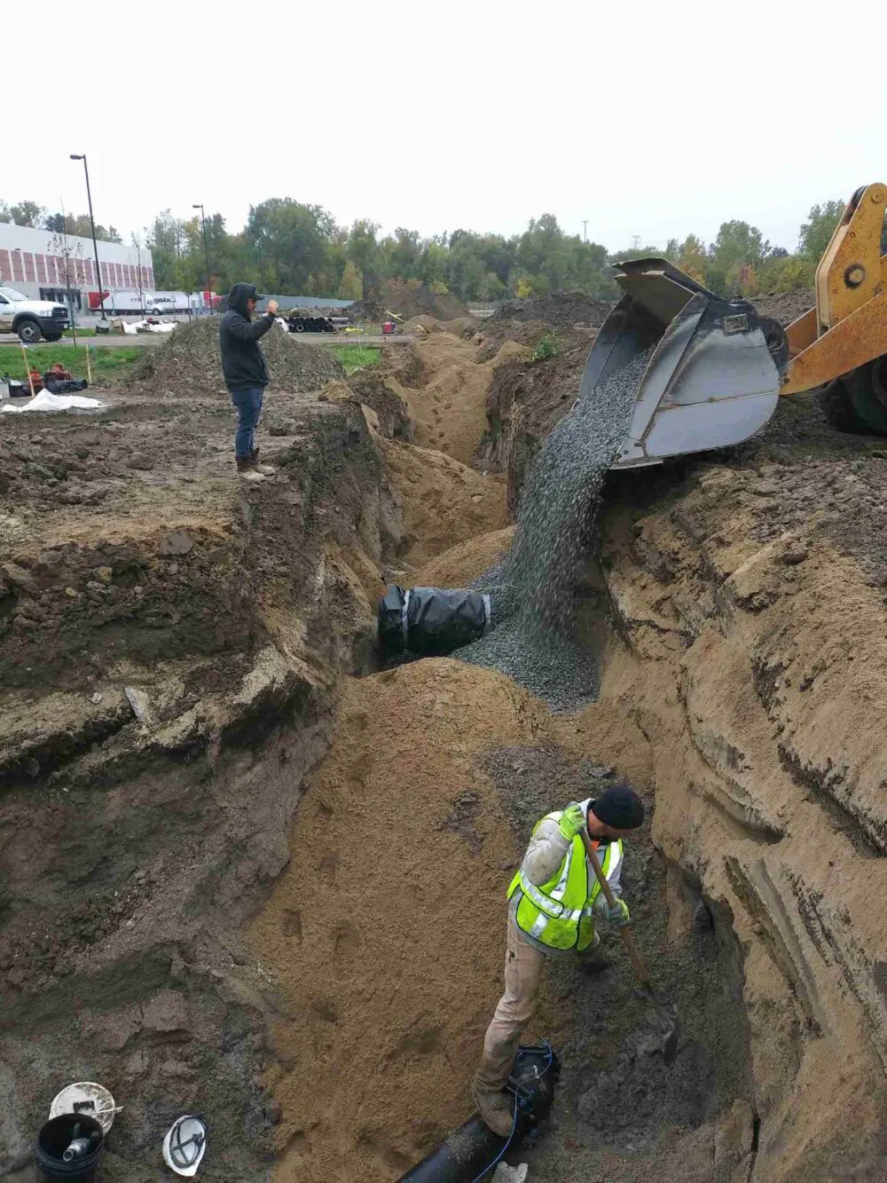 Stone bedding placed over newly installed underground pipe