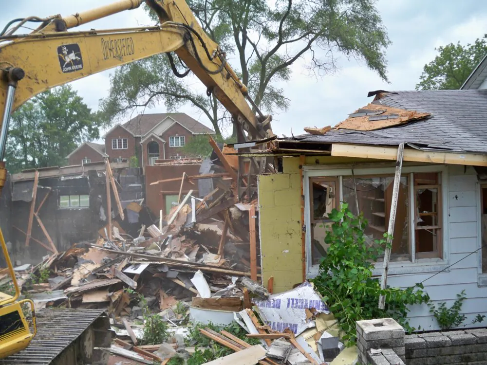 Excavator tearing down a residential structure