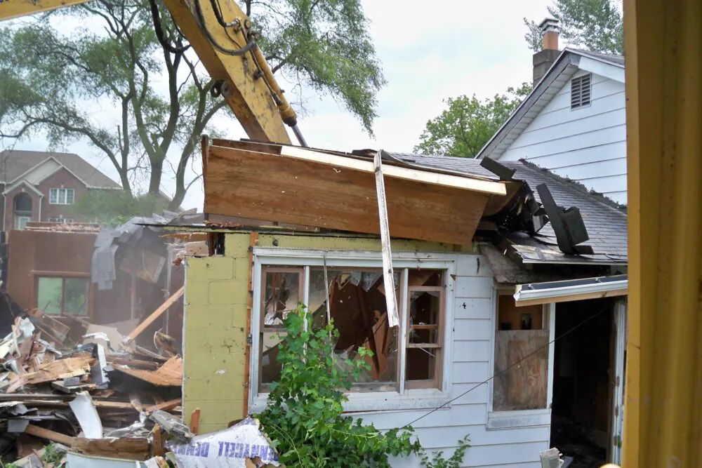 Excavator pulling apart a residential structure