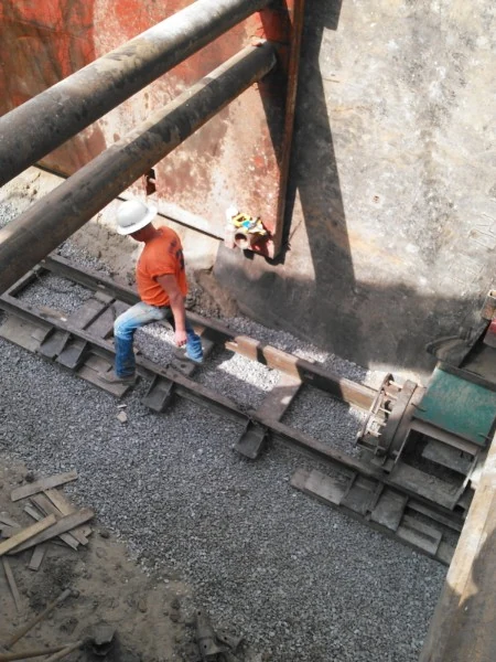 Crew member grading stone inside a shored excavation