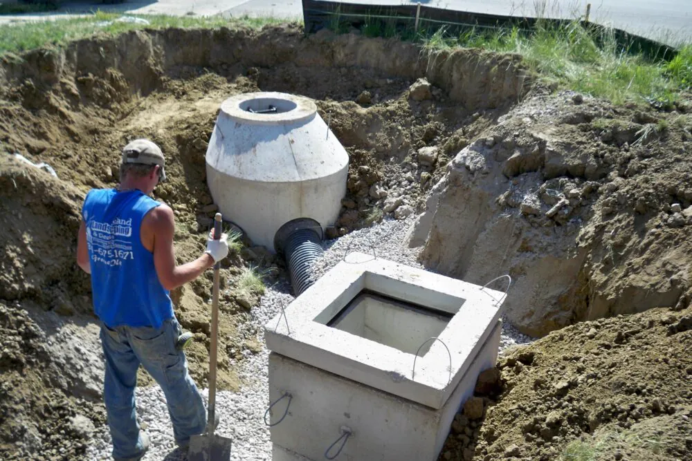 Worker setting a precast catch basin